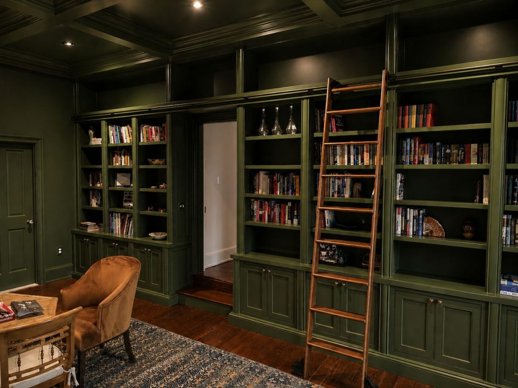 Custom built dark green library cabinet shelves with books and a custom ladder.